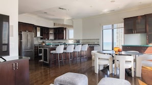 A modern kitchen with dark wood cabinets, stainless steel appliances, and a bar area with stools. - Luxury Designer Penthouse 3803 | Pool | Gold Coast (Chicago)
