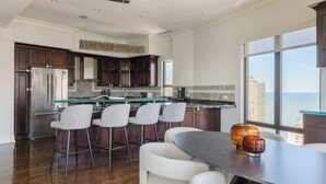 A modern kitchen with a large island, bar stools, and a view of the city. - Luxury Designer Penthouse 3803 | Pool | Gold Coast (Chicago)