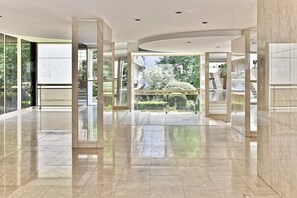 Um hall amplo com parede de vidro, teto curvo e vista para um jardim.