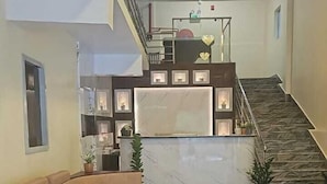 A spacious living area with a marble floor, a sofa, a staircase, and a reception desk. - HOTEL KANGAROO (Ferrurgunj)