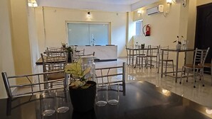 A hotel dining area with multiple tables and chairs, a reception desk, and a fire extinguisher on the wall. - HOTEL KANGAROO (Ferrurgunj)