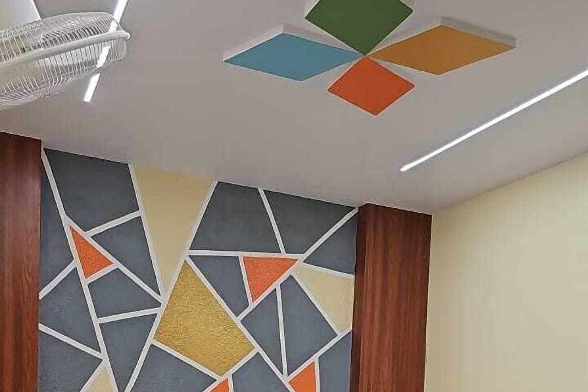 Quarto com cama, parede com padrão geométrico e luminária no teto.