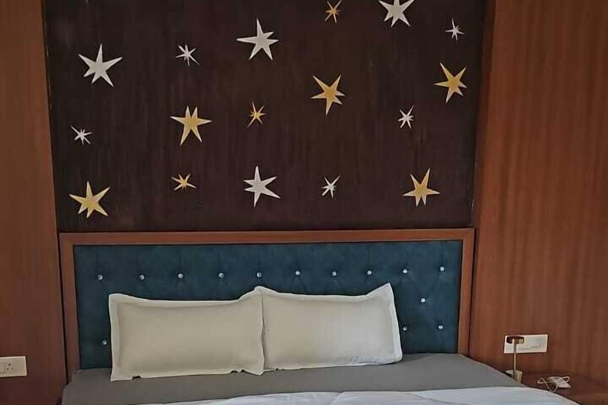 Quarto com cama, cabeceira decorada com estrelas e painel de parede de madeira.