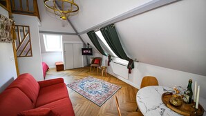 A loft-style room with a red sofa, a wooden dining table with a marble top, a patterned rug, and a ceiling light fixture. - Close to beach and amenities (Dives-sur-Mer)
