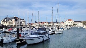 A marina with multiple boats docked, buildings in the background, and calm water. - Close to beach and amenities (Dives-sur-Mer)