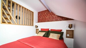 Un dormitorio con cama, ventana de listones de madera, pared con diseño y luces fijadas a la pared.