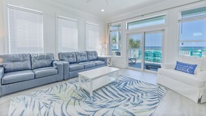Un salón amplio con un sofá de cuero azul, una mesa de centro blanca y una alfombra estampada.