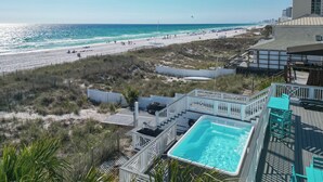 Vista a la playa con zona de piscina, una playa de arena y un edificio con balcón.
