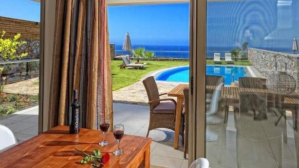 A balcony with a pool, outdoor furniture, and a view of the ocean. - Villa Kazoulis (Kalathas)