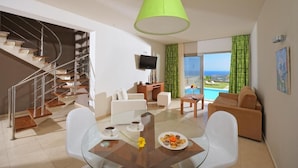 A modern living room with a glass table, white chairs, a sofa, a TV, and a view of the ocean. - Villa Kazoulis (Kalathas)