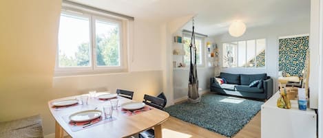 En moderne stue med spiseplads, sofa og trappe op til et loft.