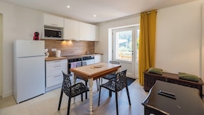 A compact kitchen with white cabinets, a microwave, a coffee maker, and a dining table with chairs. - Terrace, charm & nature in the heart of Lannion (Lannion)