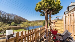 A wooden deck with a small tree, a wooden fence, and a river in the background. - Terrace, charm & nature in the heart of Lannion (Lannion)