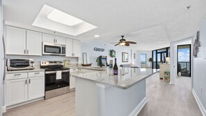Une cuisine moderne avec des armoires blanches, un grand îlot central et un ventilateur de plafond.