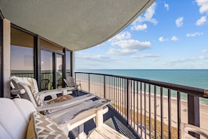 A balcony with a view of the beach, a table, and two chairs. - Family-Friendly Oceanfront Condo at Compass Cove Resort in Myrtle Beach! (Myrtle Beach)