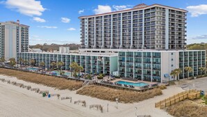 Un hôtel à plusieurs étages doté d’une piscine, d’un accès à la plage et offrant une vue sur l’océan.