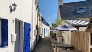 Eine enge Straße mit weißen Gebäuden, blauen Türen und einer hölzernen Bank.