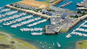 Eine Luftaufnahme eines Yachthafens mit zahlreichen vor Anker liegenden Booten, einem Parkplatz und einem kleinen Gebäude.