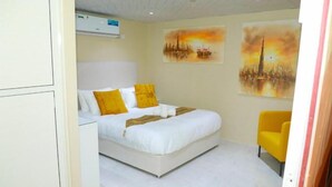 Un dormitorio con una cama, una silla y dos cuadros en la pared.