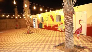 Un patio con piso a cuadros, palmeras y una estatua de flamenco.