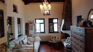 A spacious living room with a chandelier, wooden furniture, and a fireplace.