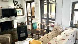A living room with a fireplace, a sofa, a television, and a large window.