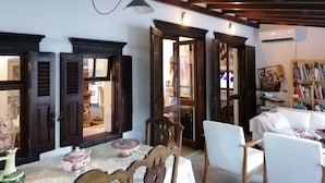 A room with exposed wooden beams, a white sofa, a table with decorative items, and a bookshelf.