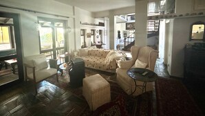 A spacious living room with a sofa, armchairs, a coffee table, and a television. There is a staircase leading to an upper level.