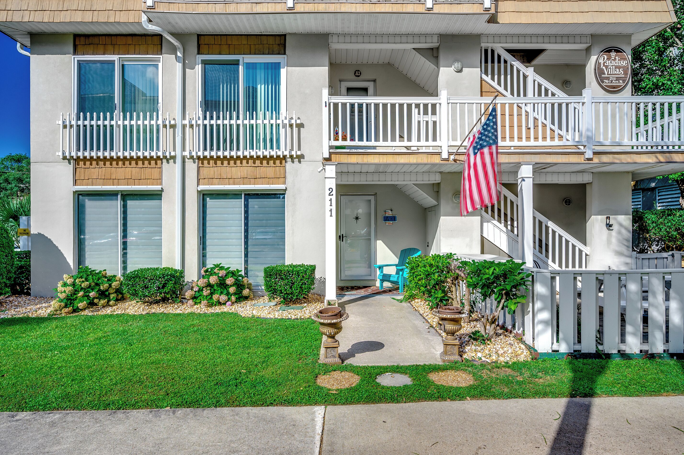 A two-story building with a balcony, a flag, and a sign that reads "Paradise Villas."
