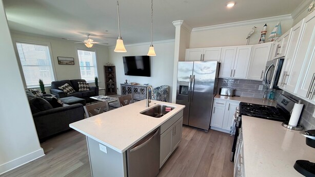 A modern kitchen with a central island, stainless steel appliances, and a dining area with a sofa and table. - Southview Condominiums unit 203 Wildwood Newest Building! With a private pool (Wildwood)