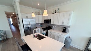 A modern kitchen with white cabinetry, stainless steel appliances, and pendant lighting. - Southview Condominiums unit 203 Wildwood Newest Building! With a private pool (Wildwood)