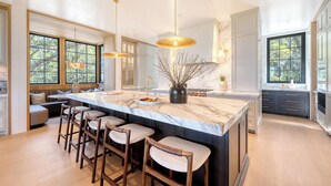 A spacious kitchen with a large island, bar stools, and pendant lighting.