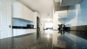 A modern kitchen with white cabinets, a black countertop, and a stainless steel range hood. - Colwell 4 Bedroom 3 Bathroom House (Derby)