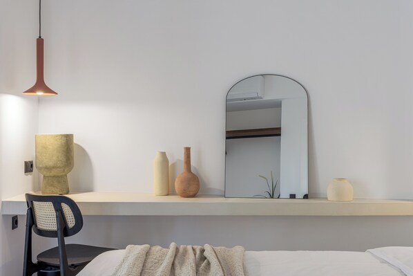 Une chambre à coucher moderne avec un lit, une chaise, une table de chevet avec une lampe et un miroir.