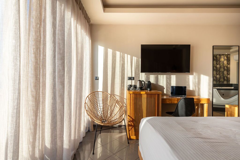 A hotel room with a bed, a desk with a computer, a chair, a television, and a coffee maker.