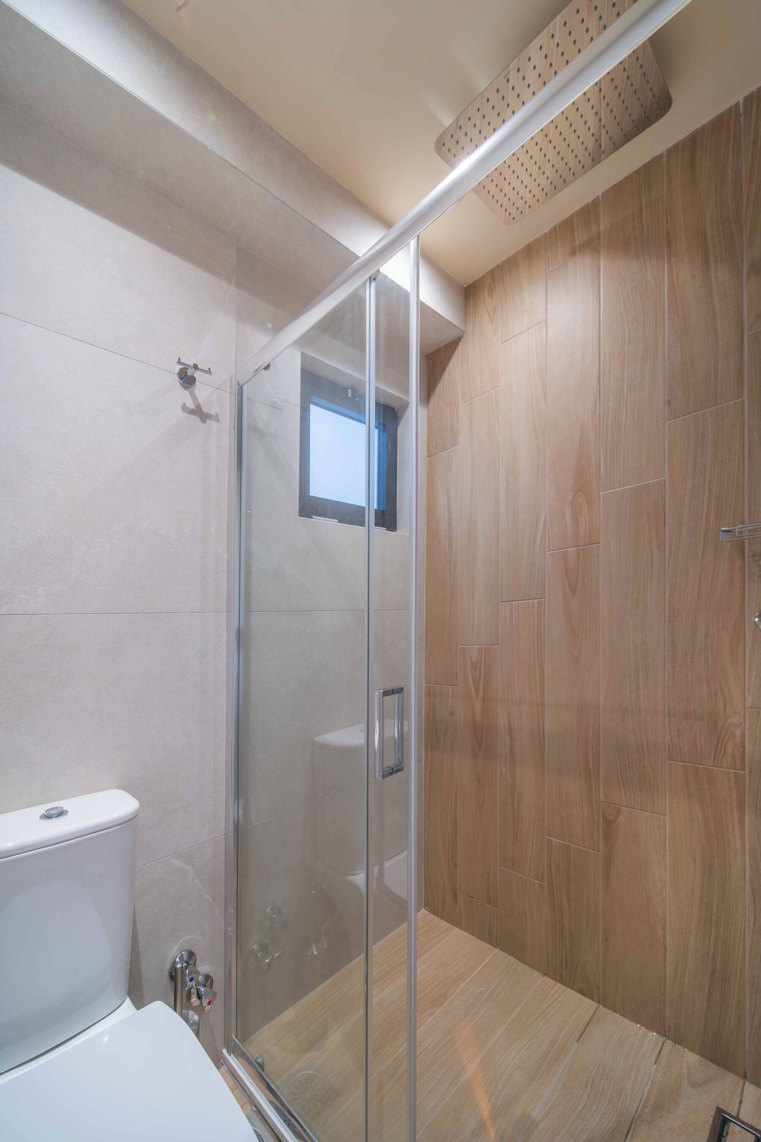 Un bagno moderno con box doccia in vetro, pavimento in legno e vaso WC bianco.