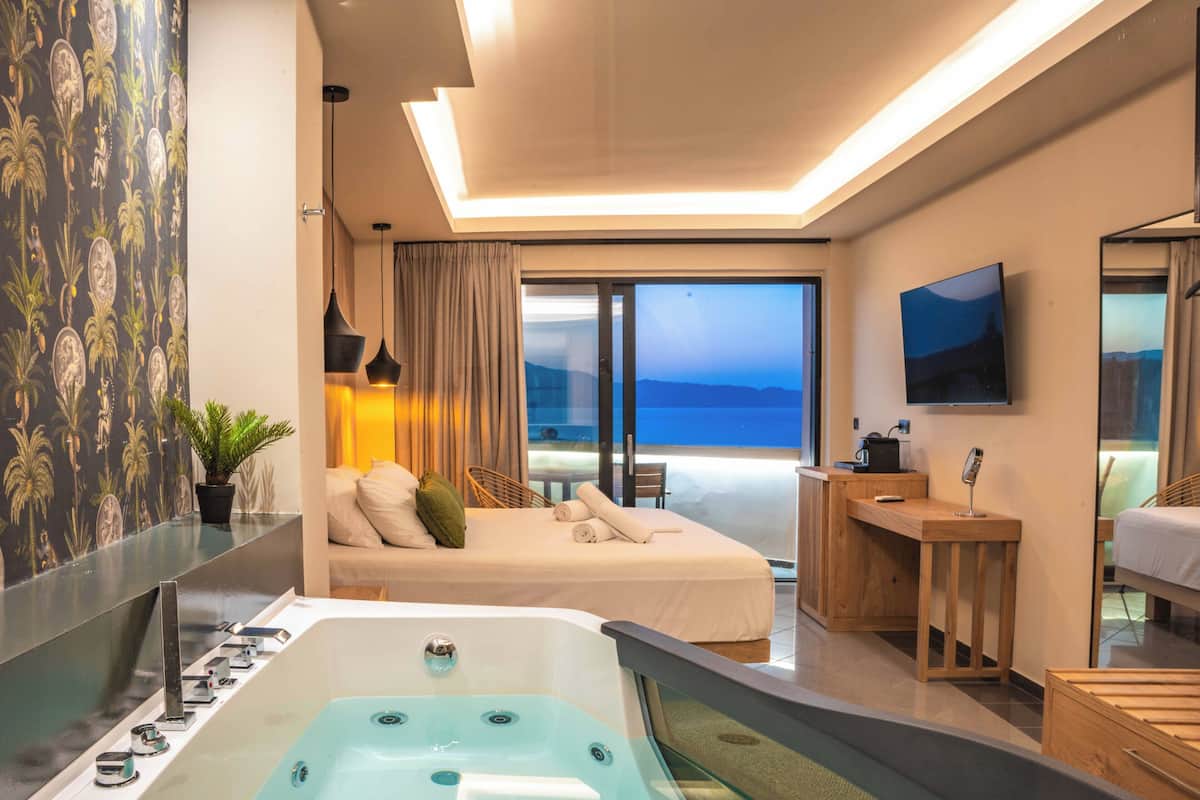 Habitación de hotel moderna con una cama grande, zona de estar, escritorio, bañera y televisión.