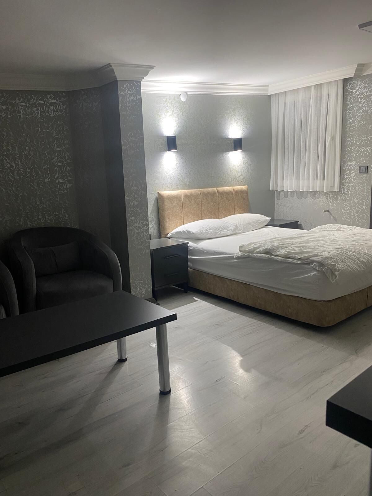 A bedroom with a bed, a chair, a nightstand, and a desk.