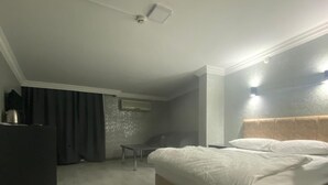 A modern bedroom with a large bed, a dark dresser, and a small table.