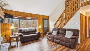 A spacious living room with wooden floors, two leather sofas, a fireplace, and a wooden staircase. - Come stay! Sam's Cabin is a genuine mountain treasure. (Canaan Valley)
