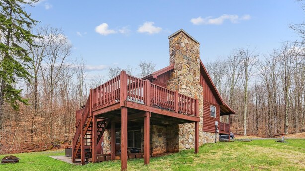 A cabin with a stone chimney, wooden deck, and a staircase leading to a balcony. - Come stay! Sam's Cabin is a genuine mountain treasure. (Canaan Valley)
