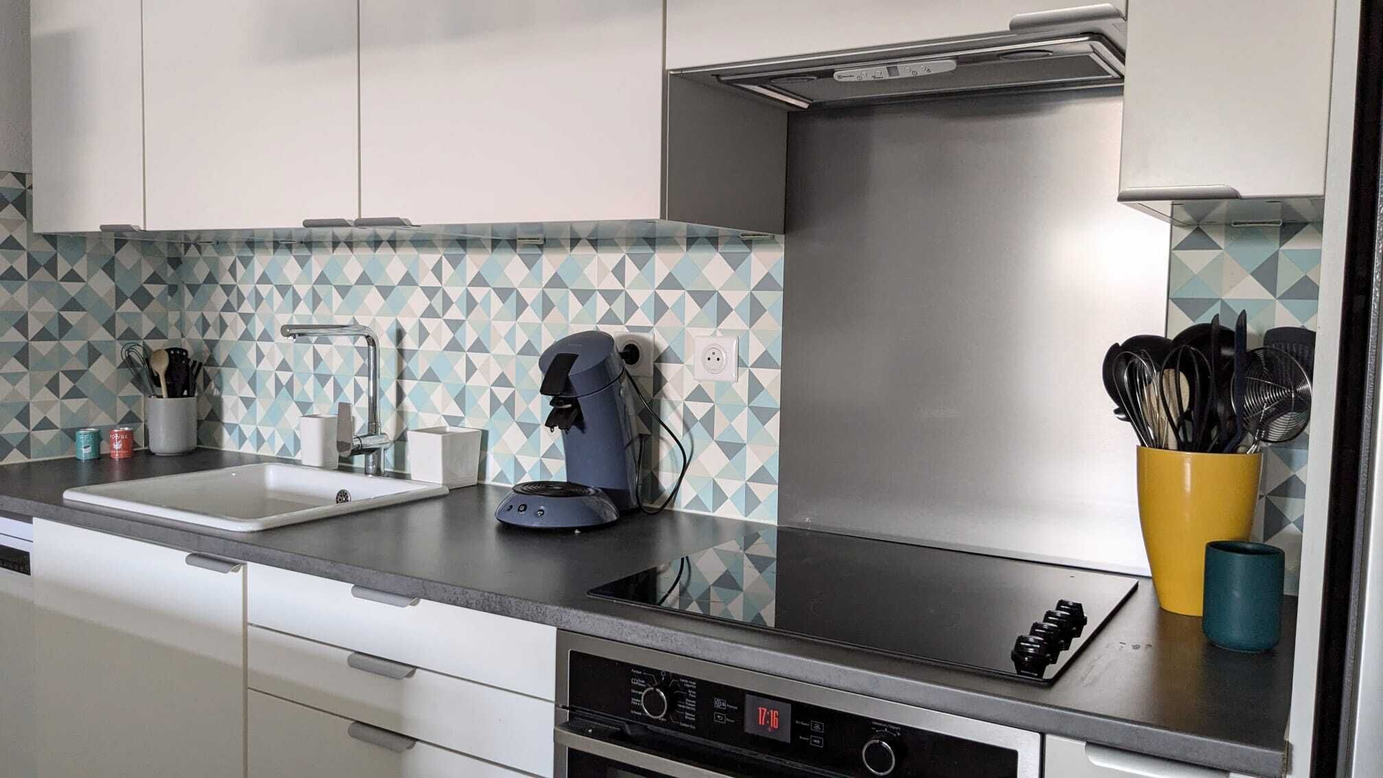 Een moderne keuken met een vaatwasser, koffiezetapparaat en keukengerei op het aanrecht.