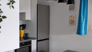 Una cocina moderna con un refrigerador empotrado, una encimera gris y tres lámparas colgantes.