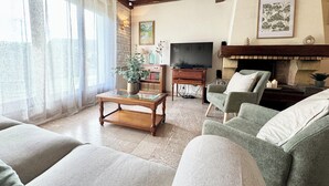 A living room with a fireplace, a television, and a bookshelf. - La Baraque de Papi - Spacious detached house - Private garden (Marck)