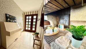 A room with a piano, a door with glass panels, a stone fireplace, and a potted plant. - La Baraque de Papi - Spacious detached house - Private garden (Marck)