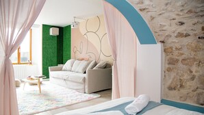 Una camera da letto con un letto, un divano, un tavolino e una parete verde decorativa.