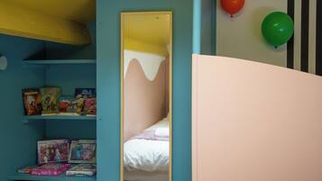 Une chambre à coucher avec un lit, une étagère remplie de jouets et un miroir.