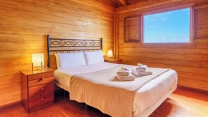 Een slaapkamer met houten lambrisering, een bed, nachtkastjes en een raam.