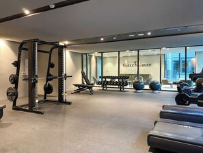 A gym with weightlifting equipment, dumbbells, and exercise balls.
