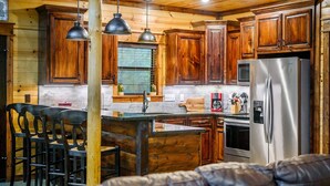 A kitchen with wooden cabinets, a stainless steel refrigerator, and pendant lighting. - Sugar Mama - great location, sleeps 10, hammocks (Broken Bow)